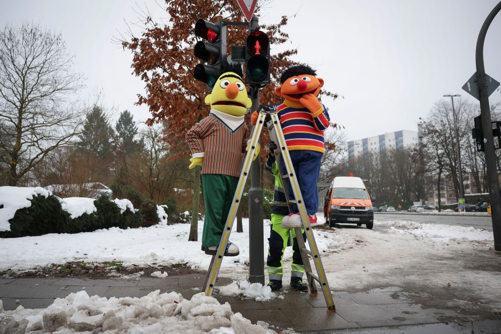 Dos figurantes interpretan a los personajes Ernie y Bert (Epi y Blas, o Enrique y Beto, en las versiones de habla española), de la serie infantil "Sesame Street" durante el montaje del semáforo que incorpora sus perfiles en un cruce viario de la ciudad alemana de Hamburgo. Crédito Christian Charisius/dpa