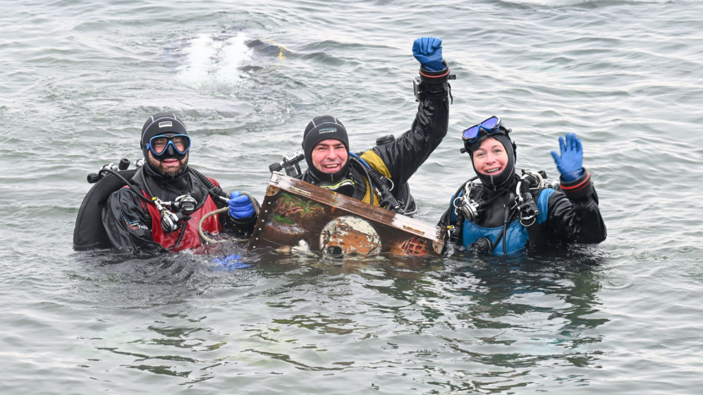 Maren Wagenbreth (der.), Thomas Wagenbreth y Georg Häussler (izq.) sacan del lago de Constanza el cofre de madera durante la tradicional inmersión de los Reyes Magos. Crédito Felix Kästle/dpa